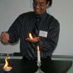 Gavin performing a chemistry demonstration, holding fire in his hand.